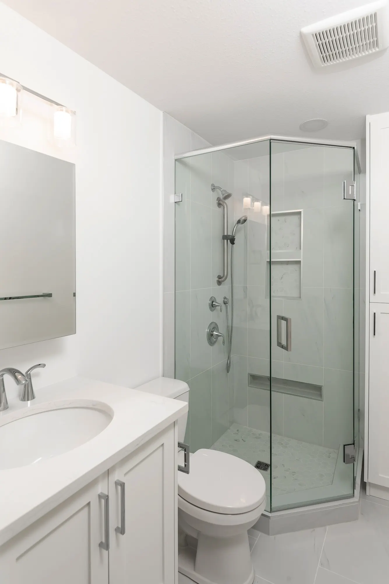 Bright white family bathroom with corner glass shower in Chilliwack